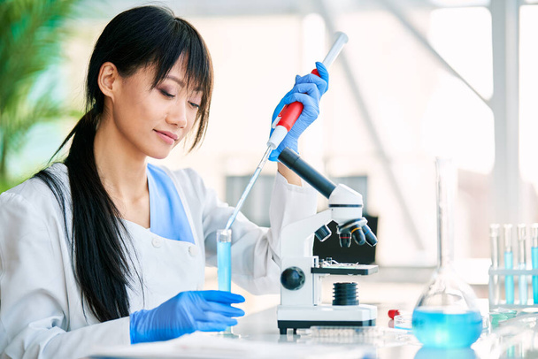 Beautiful female scientist preparing and analyzing microscope slides working in modern science laboratory. Chemistry, Medicine, Biotechnology concept - Foto, immagini