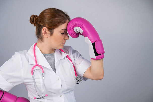 Woman doctor in pink boxing gloves on a white background - Photo, image