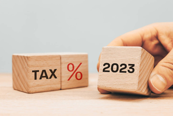 расчет налогов в 2023 году, деревянный блок с датой представления налоговой декларации, слово TAX и символ процента - Фото, изображение