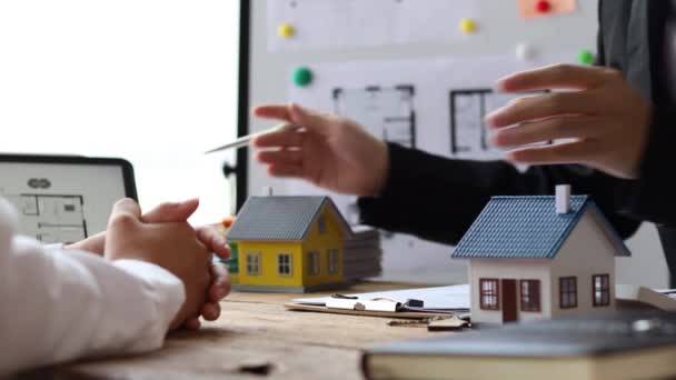 Agenti immobiliari spiegano modelli di immobili in progetti da elaborare ai clienti, spiegando e presentando informazioni sulle case e l'acquisto di prestiti. Concetto di trading immobiliare. - Filmati, video