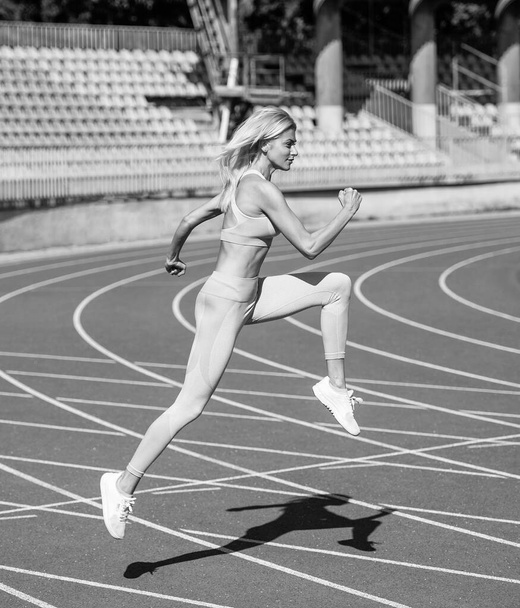 woman sport trainer in motion. speed and energy. stamina. sexy runner in fitness sportswear. sprinting on outdoor arena racetrack. training and workout. athletic female coach running. - Photo, image