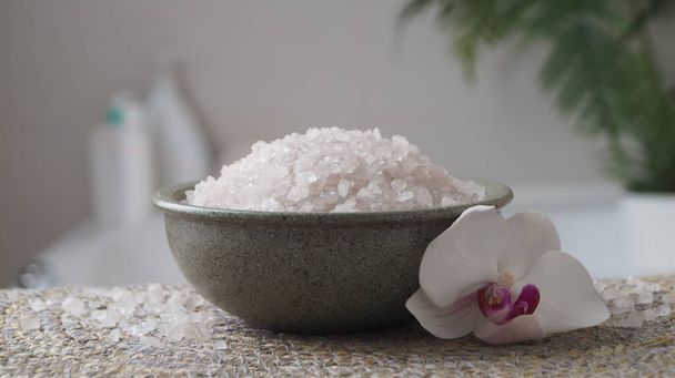Bowl with bath salt and flower on wicker mat indoors, closeup - Фото, изображение