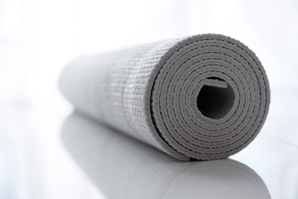 Rolled karemat or fitness mat on tiled floor, closeup - Фото, изображение