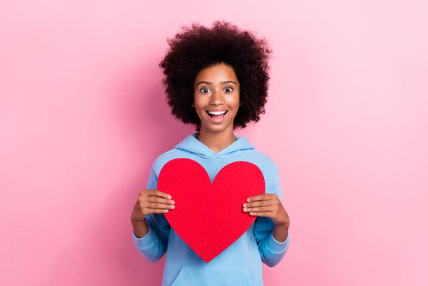 Portrait of funny amazed girl toothy smile hold large red paper heart card isolated on pink color background. - Φωτογραφία, εικόνα