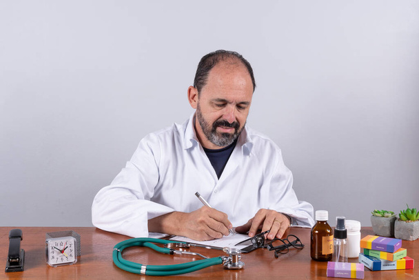 Porträt eines reiferen Oberarztes, der auf Rezept schreibt - Foto, Bild