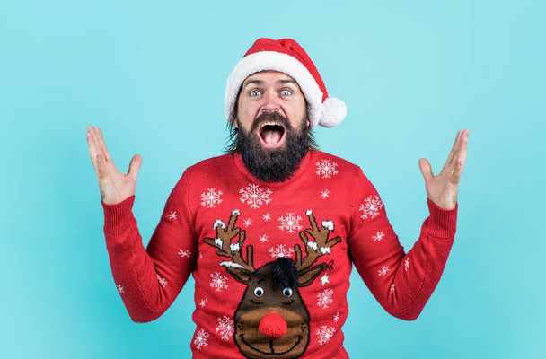 amazed bearded man in santa claus hat and knitted sweater celebrate new year winter holiday, xmas surprise. - Photo, image