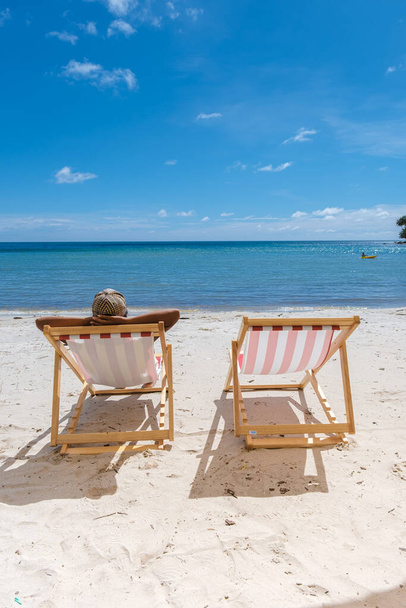Strand nyaralás koncepció székkel és kék ég a trópusi sziget Koh Kood Thaiföld. színes piros és fehér strand szék a fehér tengerparton és a kék óceán - Fotó, kép
