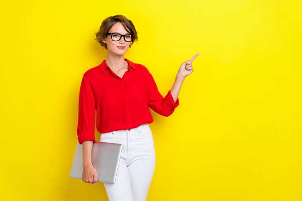 Photo of nice confident girl with bob hairstyle wear red shirt hold laptop indicating empty space isolated on yellow color background. - Foto, afbeelding