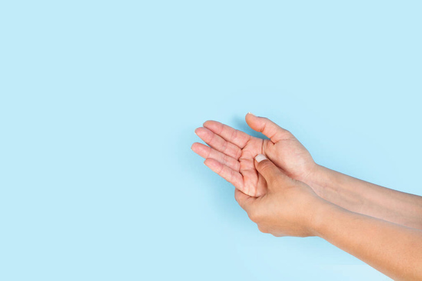 Woman doing a palm hand self masage on a light blue background with copy space - Foto, afbeelding
