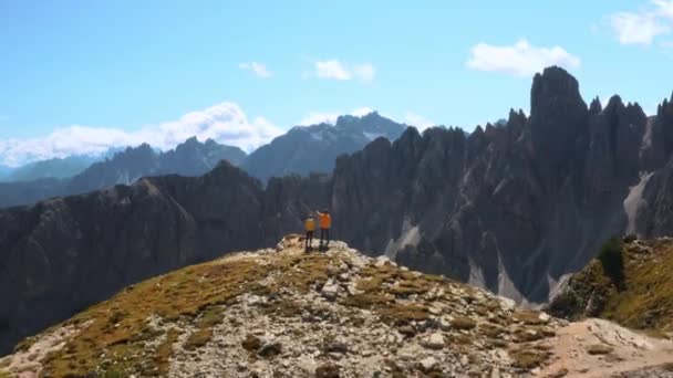 Άνδρας τουρίστας δείχνει χέρι με τον ορίζοντα. Γυναίκα ταξιδιώτης κοιτάζει ορεινό τοπίο του Three Peaks της Lavaredo μέσα από κιάλια εναέρια άποψη - Πλάνα, βίντεο