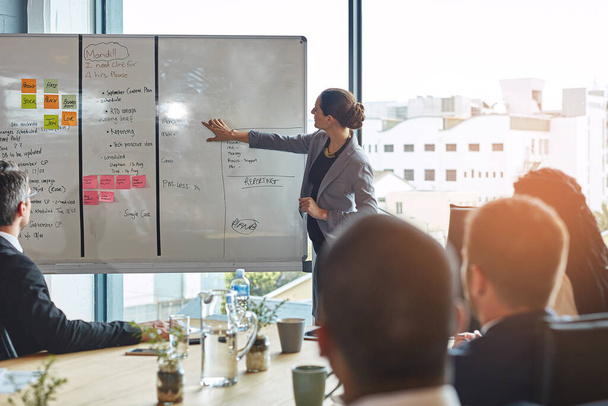 She knows her business. an executive giving a whiteboard presentation to a group of colleagues in a boardroom - Photo, Image