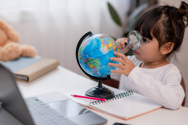 Asian little girl is learning the globe model, concept of save the world and learn through play activity for kid education at home. - Foto, Imagen