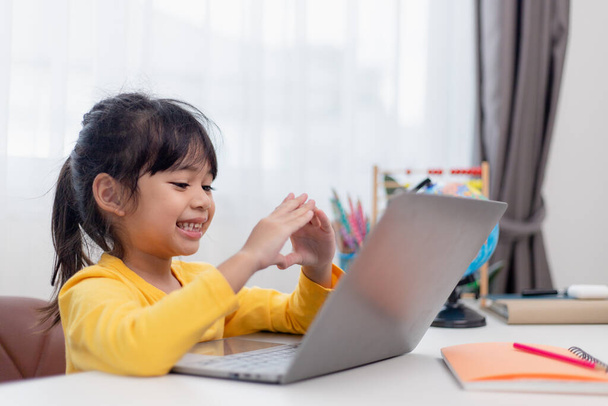 Primo giorno di scuola. Ragazzina asiatica che utilizza un computer portatile, studiando attraverso il sistema di e-learning online. - Foto, immagini