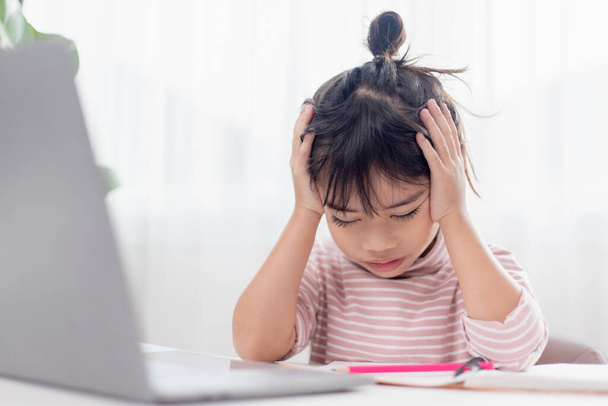 Asian child is serious about studying homework during online lesson at home, social distancing during quarantine, self-isolation, online education concept, homeschooling, study online video call teacher. - Photo, Image