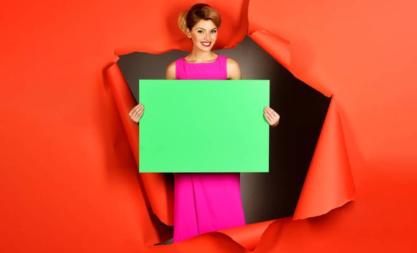 Smiling girl with advertising board. Sensual model in pink dress. Trendy clothes. Fashion product - Photo, image