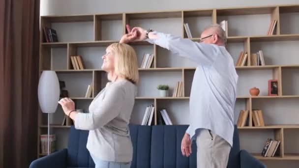 Beautiful elderly couple having fun at home, dancing and hugging. The love of grandfather and grandmother. A happy family in old age - Footage, Video