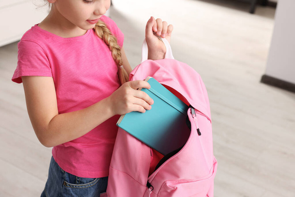 Little girl putting notebook in pink backpack at home, closeup - Zdjęcie, obraz