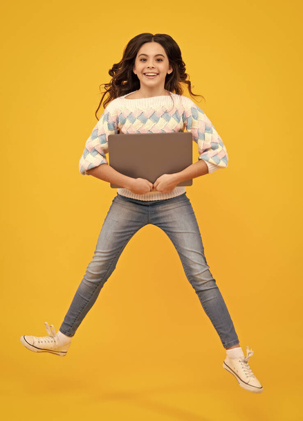 学校に戻ると、ノートパソコンを持つティーンエイジャーの学校の女の子。子供たちをジャンプさせて - 写真・画像