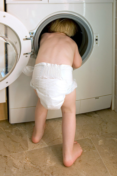 fiatal gyerek mászó belső rész egy mosógép - Fotó, kép