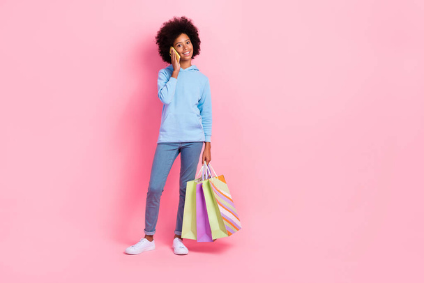 Full length portrait of cute cheerful girl speak communicate telephone hold bags empty space isolated on pink color background. - Φωτογραφία, εικόνα