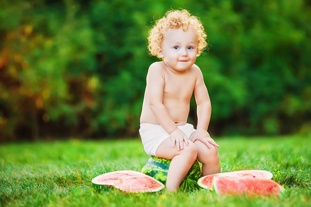 Enfant assis sur l'herbe avec une pastèque
 - Photo, image