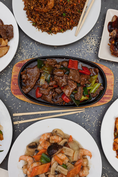 Verschiedenes chinesisches Essen. gebratener Reis, Knödel, Rindfleisch mit Austernsoße, Chopsuey. Berühmte Gerichte der chinesischen Küche auf dem Tisch. vertikale Ansicht von oben - Foto, Bild