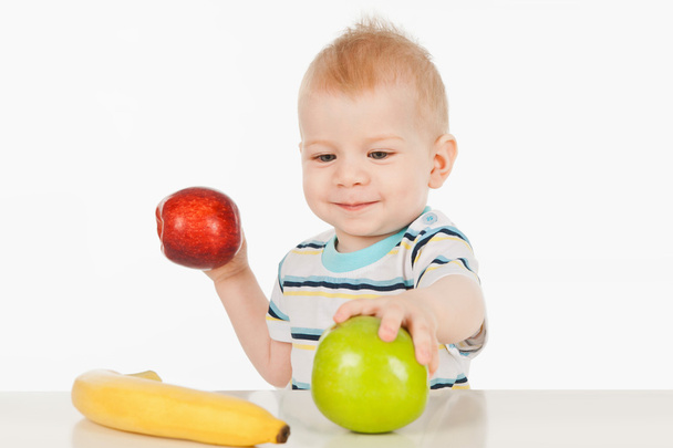 Mały chłopiec siedzi przy stole z owocami - Zdjęcie, obraz
