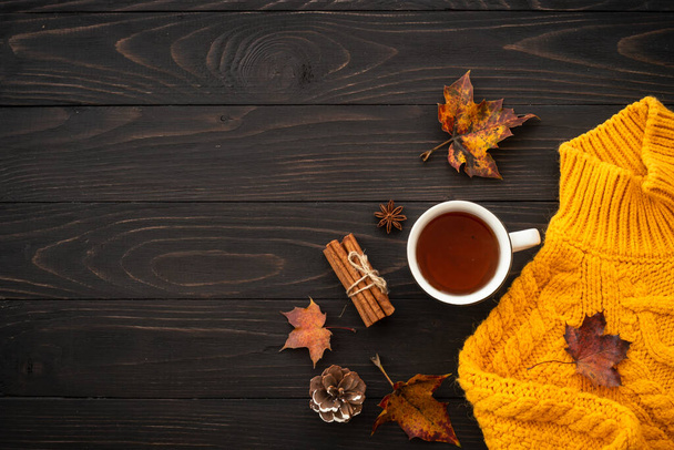 Autumn background flat lay. Knitted sweater, mug of hot tea and fall leaves on wooden background. - Fotó, kép