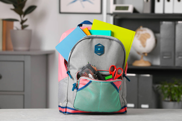Children's backpack with different school stationery on table indoors - Foto, Imagen