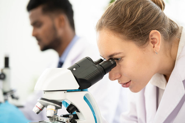 Group of Microbiologist Looking at a Lab-Grown Cultured Vegan Meat Sample in a Microscope. Medical Scientist Working on Plant-Based. medical biotechnology research laboratory using microscope. - Foto, afbeelding