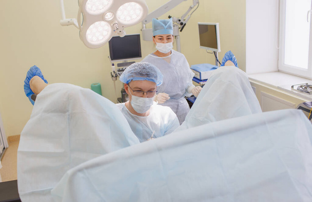 πρωκτολόγος και νοσοκόμος εκτελούν εγχείρηση στο χειρουργείο - Φωτογραφία, εικόνα