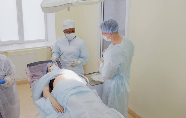 chirurg i jego asystent przygotowują się do operacji pacjenta leżącego na sali operacyjnej. - Zdjęcie, obraz