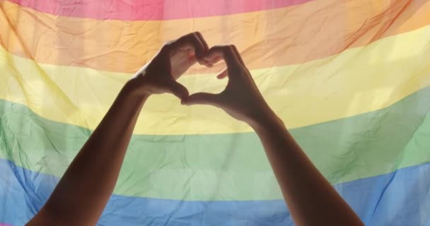 Szerelem jel. Ünnepség Esemény szimbóluma LMBT. Szerelem Egyenlő. LMBT-jogok. emberi kapcsolatok. Meleg és leszbikus büszkeség zászlót. A támogató kezek jelzik a szívet és integetnek a szivárvány zászló előtt.. - Felvétel, videó
