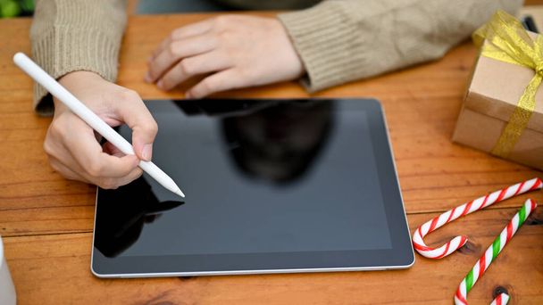 Top view image, A female freelancer in cozy sweater using her digital tablet on wooden desk. tablet black screen. - Foto, Imagen