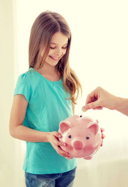 smiling little girl holding piggy bank - Фото, изображение
