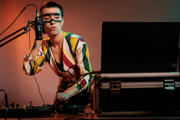 Vrouwelijke performer produceren techno muziek op mixer, met gekke make-up en spelen met audio stereo-apparatuur. Muzikant kunstenaar mengen geluiden aan draaitafels om muzikale prestaties te maken in de studio. - Foto, afbeelding