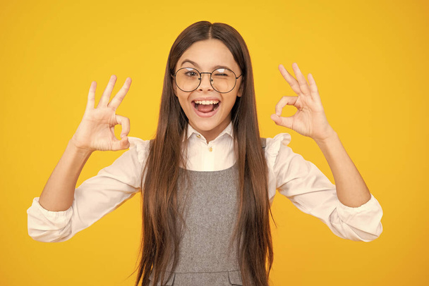 Young girl child show fingers ok symbol sign language isolated on yellow background. Funny teenager face. Excited face. Amazed expression, cheerful and glad - 写真・画像