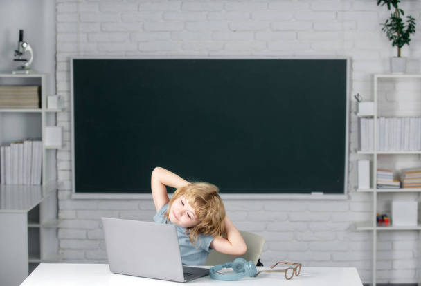 Portrait de garçon gai attrayant utilisant un ordinateur portable, se reposer et se détendre après la leçon d'école - Photo, image