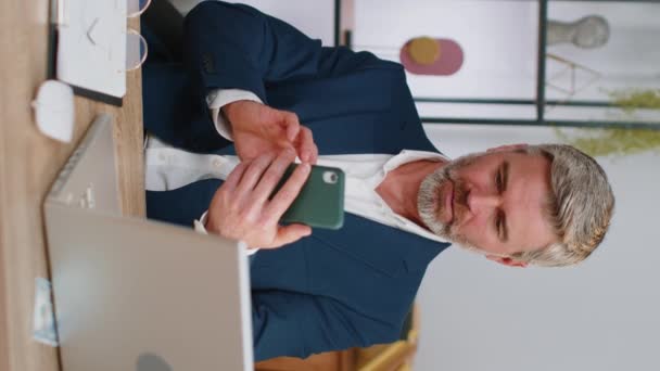 Зрілий бізнесмен у костюмі використовує смартфон, який друкує перегляд, втрати стають здивованими раптовими результатами лотереї, погані новини, втрата статку не вдається на робочому місці домашнього офісу. Чоловік середнього віку фрілансер
 - Кадри, відео
