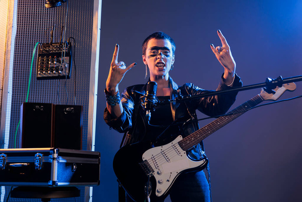 Cool taiteilija tekee rock-merkki live-esitys, laulaa kovaa vaihtoehtoista heavy metal musiikkia. Mikrofonin ja kitaran avulla voit soittaa viileää soololaulua, käyttää nahkatakkia ja näyttää rock-symbolia. - Valokuva, kuva