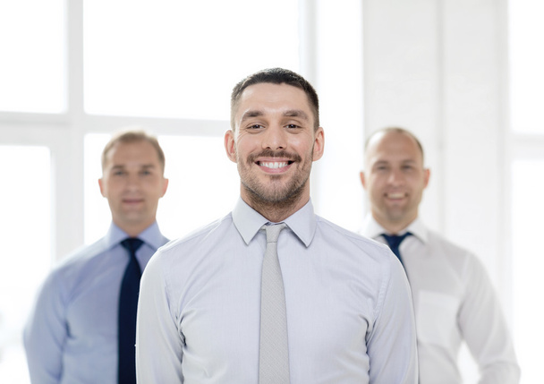 smiling businessman in office with team on back - Zdjęcie, obraz