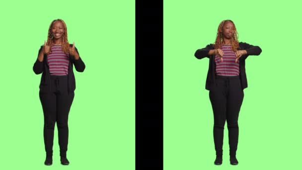 Woman on two sides of greenscreen backdrop showing thumbs up and thumbs down, doing like and dislike gesture standing with full body over background. Good positive and bad negative symbol. - Footage, Video
