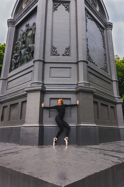 Ballerina en pointe возле черной стены
 - Фото, изображение