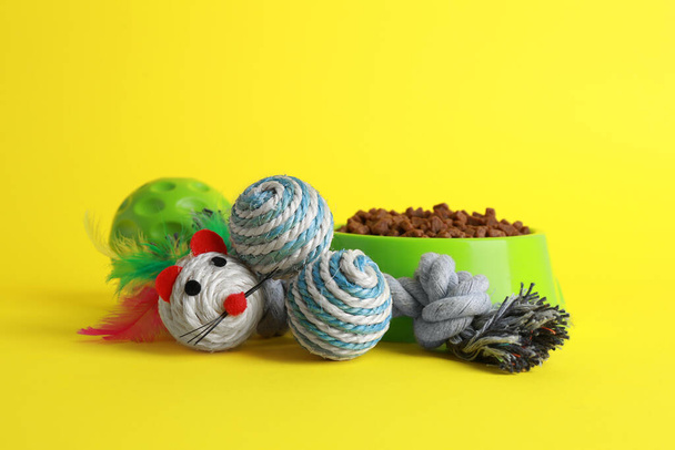 Pet toys and feeding bowl on yellow background - Фото, изображение