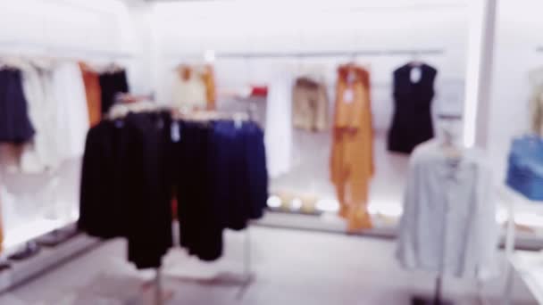 Móda, maloobchod a obchod, rozmazaný pohled na interiér oděvního obchodu v luxusním nákupním centru jako rozostřené pozadí. Vysoce kvalitní 4K záběry - Záběry, video