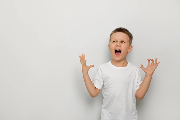 Angry little boy screaming on white background, space for text. Aggressive behavior - Zdjęcie, obraz