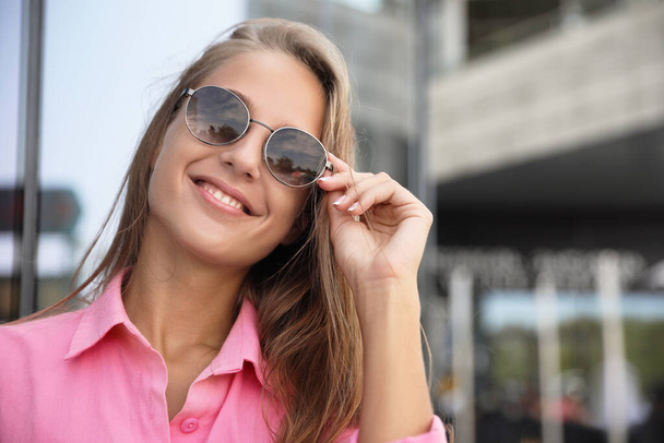 Beautiful young woman in stylish sunglasses on city street. Space for text - Foto, imagen