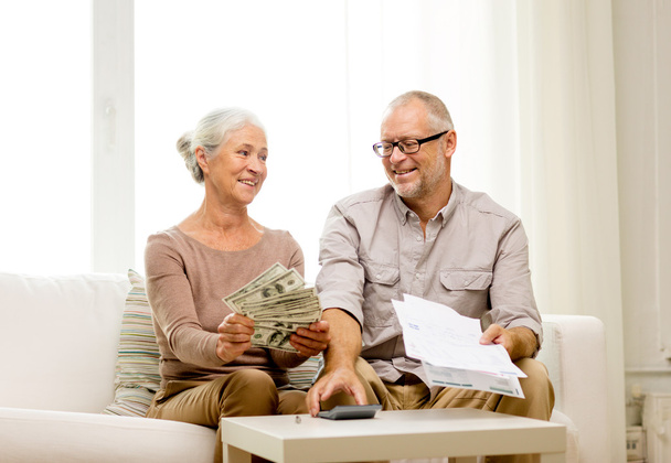 Senior paar met geld en rekenmachine thuis - Foto, afbeelding