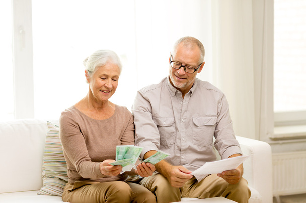 senior couple with money and calculator at home - Foto, afbeelding