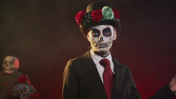 Жуткая богиня в костюме на Хэллоуин с черепом, прославляющая святую мексиканскую традицию, позирующая в студии. Выглядит как женщина смерти на ритуальном празднике Санта-Муэрте. Портативный выстрел. - Кадры, видео